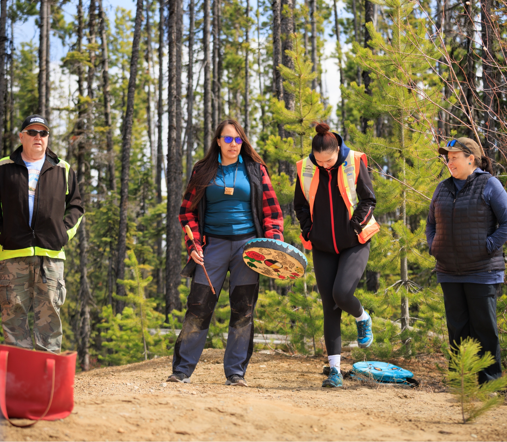 Individuals in traditional Indigenous regalia participating in a cultural ceremony featuring a bear headdress.