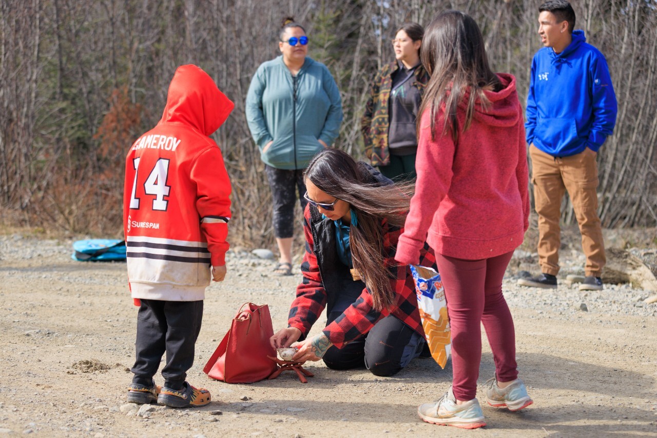 Individuals in traditional Indigenous regalia participating in a cultural ceremony featuring a bear headdress.